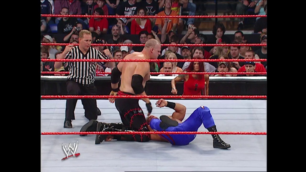 A frame from WWE Raw (May 9, 2005) at 40:50. A WWE wrestler in blue pants lies on the red-roped ring while a shirtless opponent stands nearby. A referee in striped shirt officiates as the crowd watches from the stands.