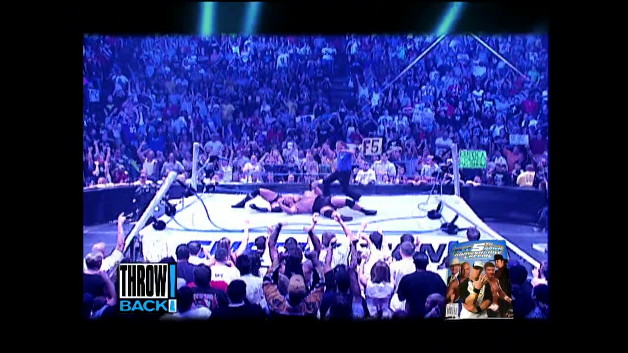 A frame from WWE SmackDown (September 16, 2004) at 25:14. A wrestling ring filled with multiple wrestlers in action, surrounded by an enthusiastic crowd under dramatic blue lighting. The "Throwback" graphic is visible in the lower left corner, indicating this is archival WWE SmackDown footage.