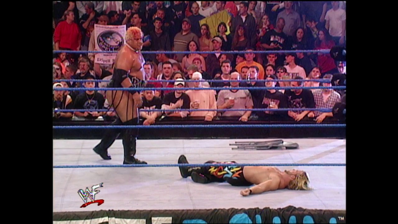 A frame from WWE SmackDown (November 2, 2000) at 50:50. A professional wrestler lies motionless on the mat while an opponent stands nearby in the WWF ring. The crowd watches from the stands as the match unfolds, with the WWF logo visible on the canvas.