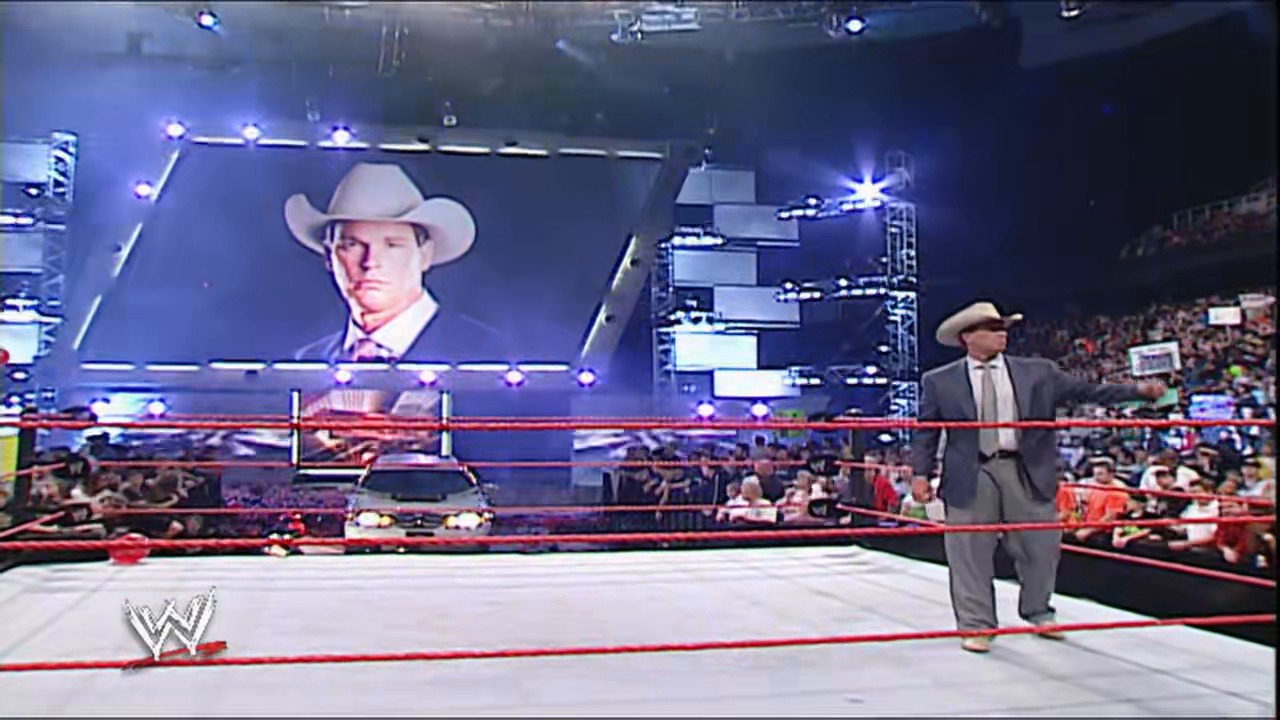 A frame from WWE Raw (December 31, 2007) at 40:36. A WWE Raw broadcast features a man in a cowboy hat and business suit standing in the ring, with a large video screen displaying his portrait above. The arena is filled with spectators, and the WWE logo is visible in the corner.