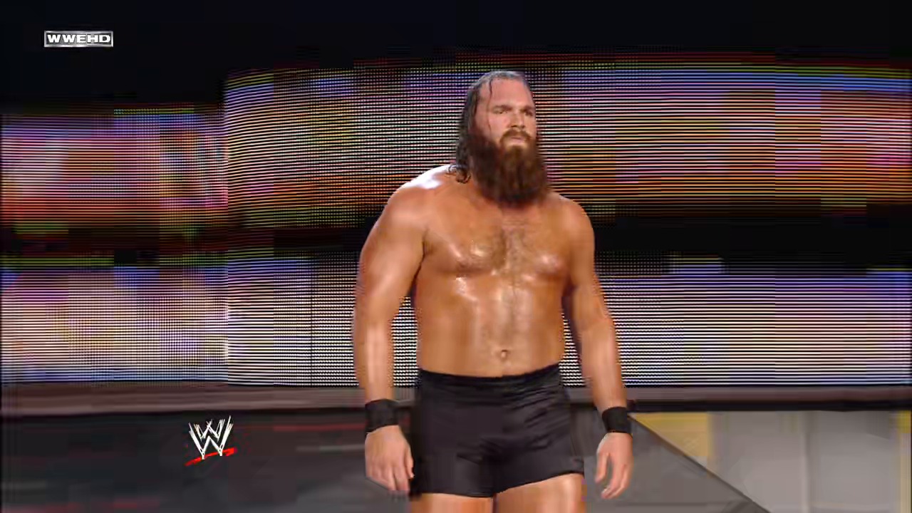 A frame from WWE Raw (February 9, 2009) at 39:04. A shirtless wrestler with long dark hair and a beard stands on the WWE Raw stage, wearing black shorts and wristbands. The LED screen backdrop displays colorful horizontal scan lines, with the WWE logo visible in the lower left corner.