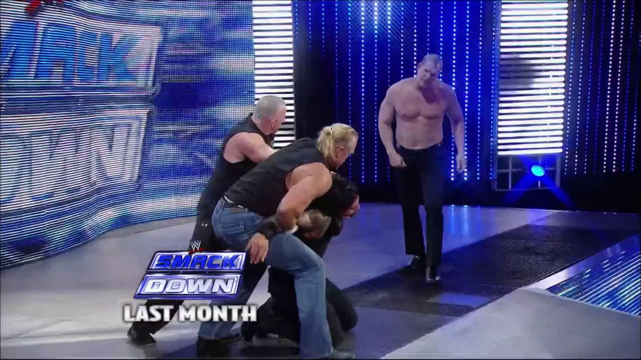 A frame from WrestleMania XXX (2014) at 1:07:28. # WWE SmackDown Scene

Professional wrestlers engage in action on a blue-lit WWE SmackDown stage, with one performer executing a move on an opponent while another watches. The broadcast graphics and LED backdrop display the show's branding.