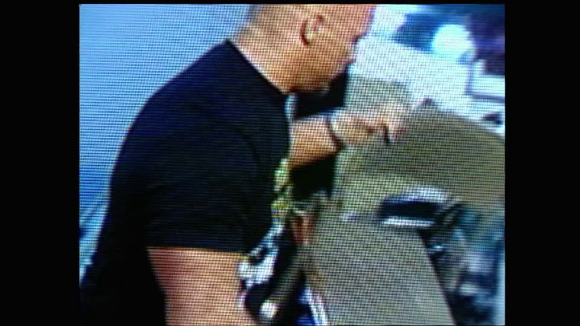 A frame from WWE Raw (August 16, 1999) at 1:00. A wrestler in dark attire executes a move against an opponent in the ring during WWE Raw. The image captures the intense action with visible crowd and arena atmosphere in the background.