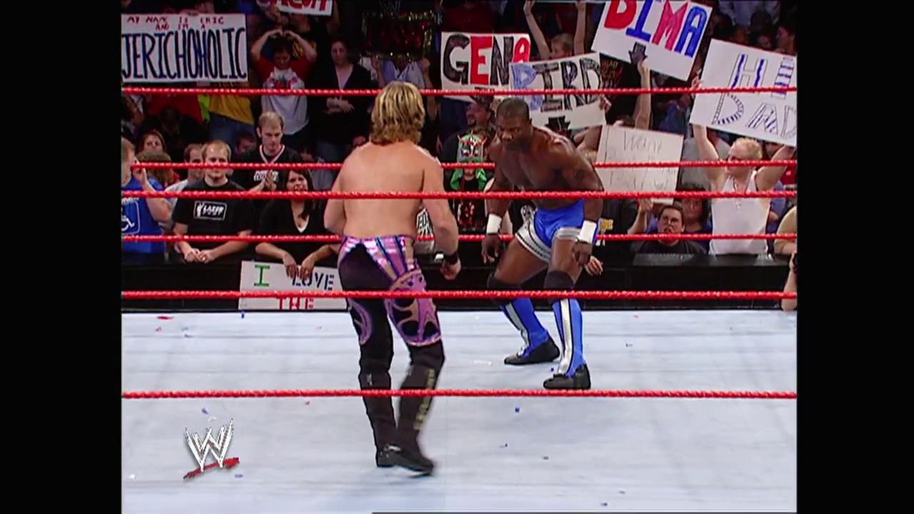 A frame from WWE Raw (October 25, 2004) at 27:08. Two wrestlers face off in a WWE Raw match inside the red-roped ring, with an enthusiastic crowd holding signs visible in the background. The WWE logo appears in the lower left corner of the broadcast.