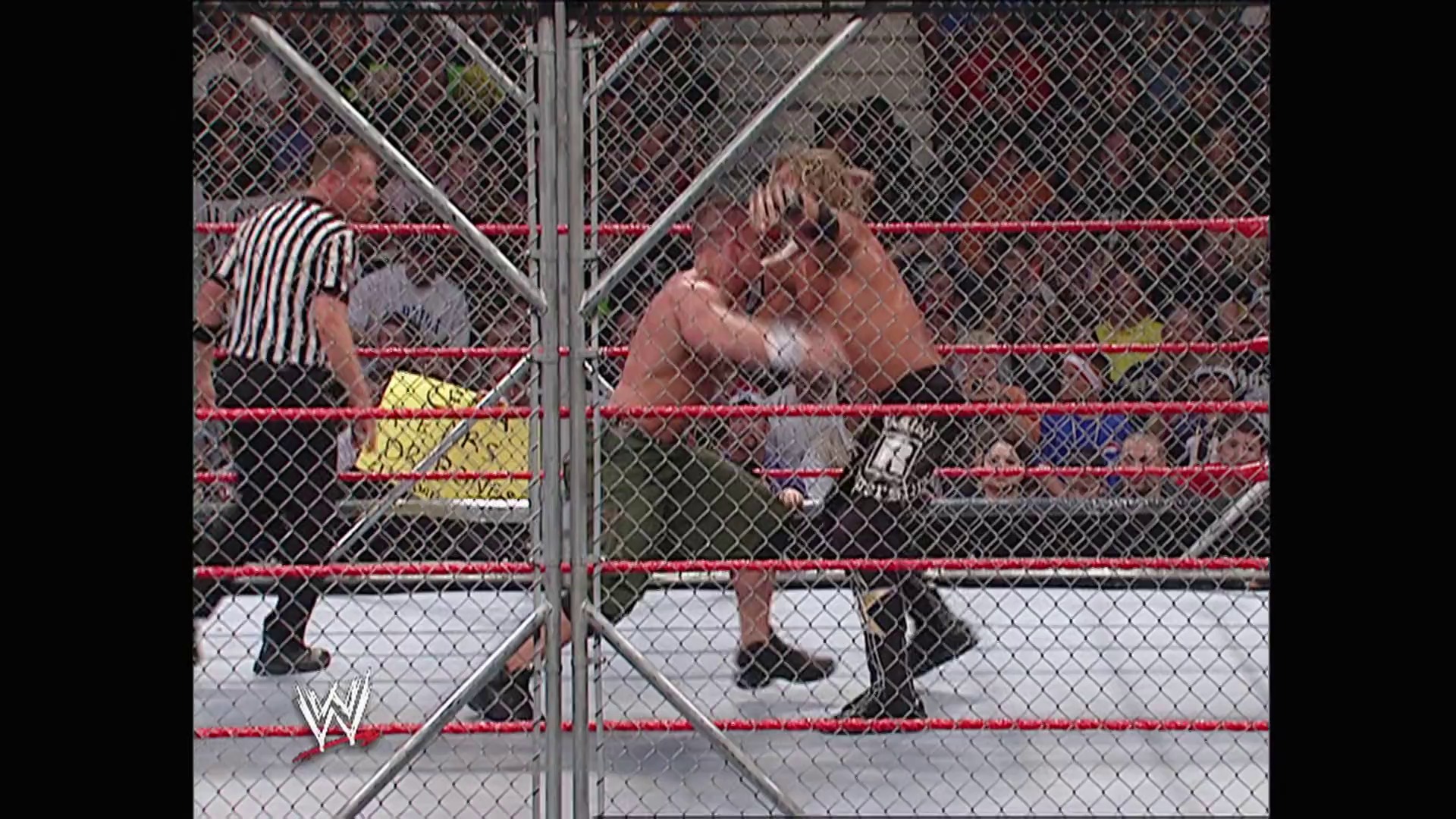 A frame from WWE Raw (October 2, 2006) at 1:17:27. A Hell in a Cell match featuring two wrestlers inside the steel cage structure with red ropes visible. A referee in striped shirt stands nearby as one wrestler appears to be in an aggressive stance during the intense match.