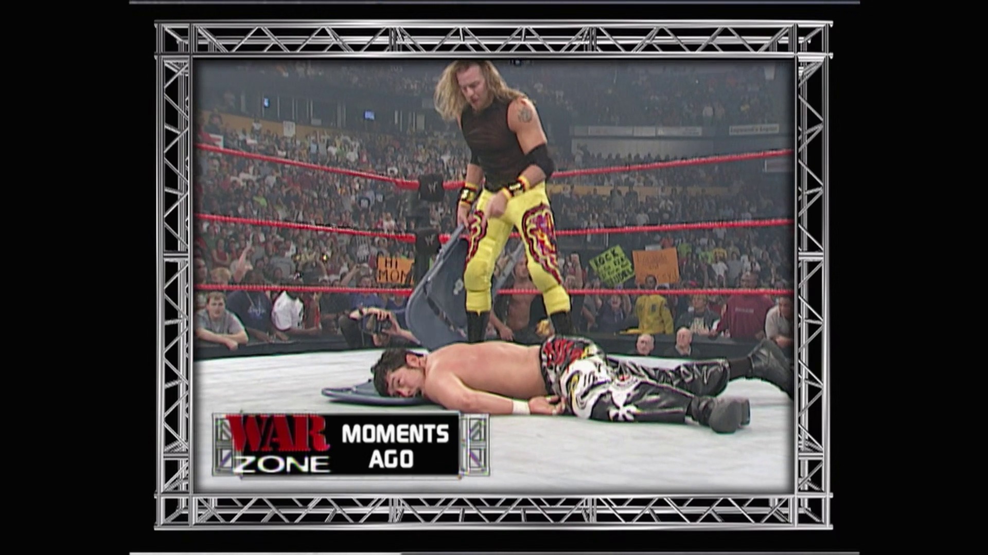 A frame from WWE Raw (September 17, 2001) at 1:08:01. A wrestler in yellow and red leg gear stands over a fallen opponent in the WWE Raw ring, with a packed crowd visible in the background. The "War Zone Moments Ago" graphic appears at the bottom of the broadcast screen.