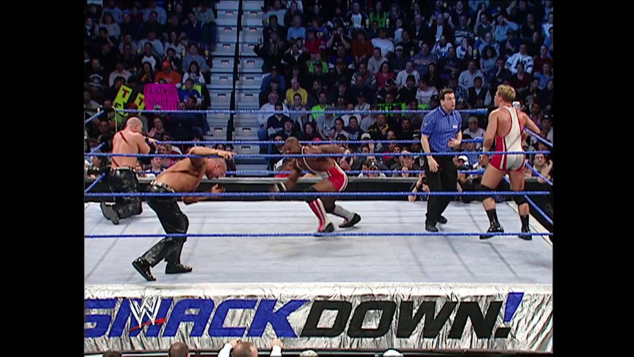 A frame from WWE SmackDown (January 15, 2004) at 36:02. # WWE SmackDown Ring Action

A multi-wrestler match unfolds in the blue-roped WWE ring with several competitors in action—some standing, others on the canvas. The crowd fills the arena stands in the background while the "SmackDown" logo displays prominently at the ring's edge.