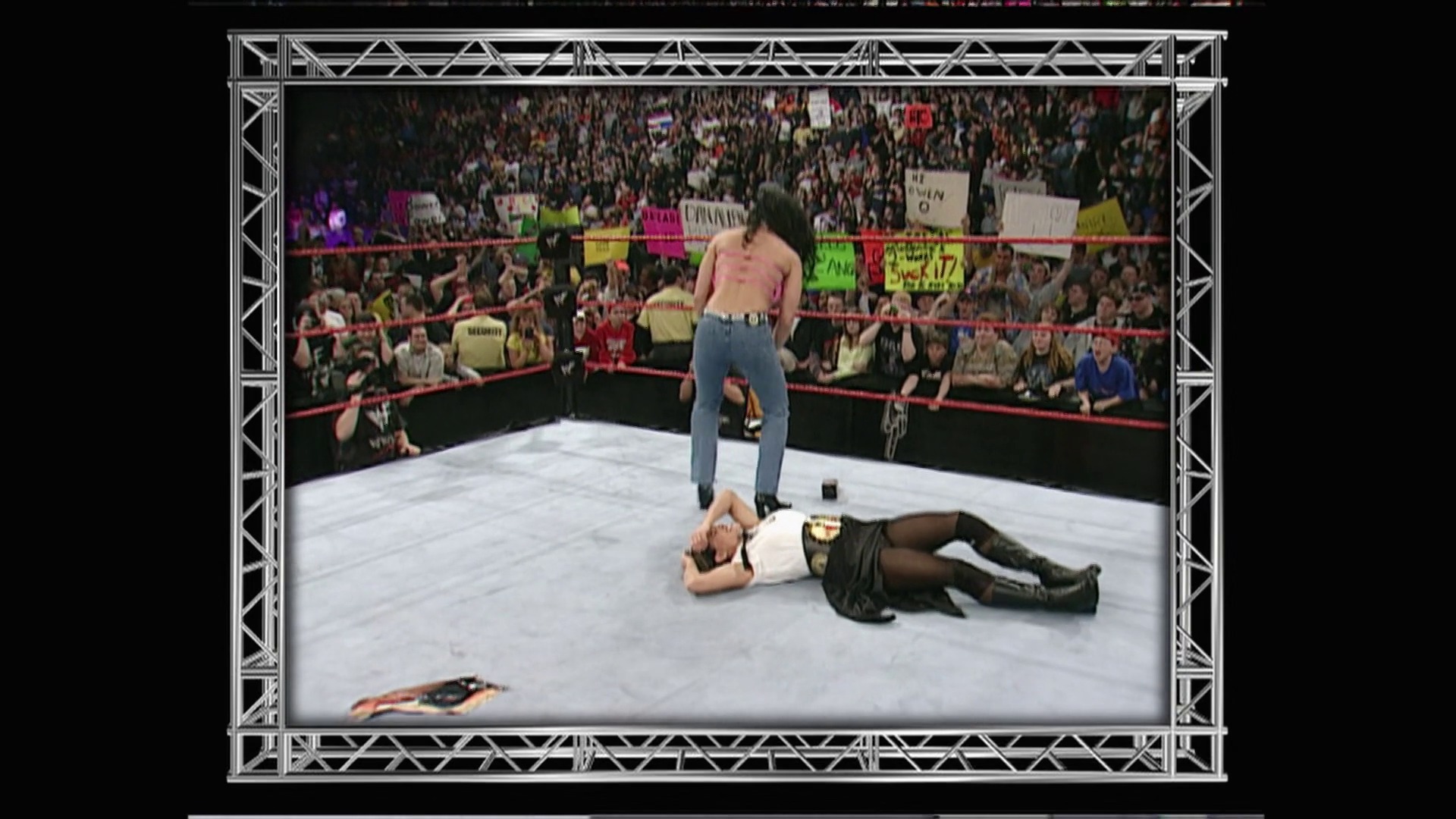 A frame from WWE Raw (March 19, 2001) at 1:06:25. # WWE Raw Match Scene

A shirtless wrestler stands over a fallen opponent wearing a championship belt in the WWE ring, with a packed crowd visible behind the red ropes and arena lighting illuminating the white mat.