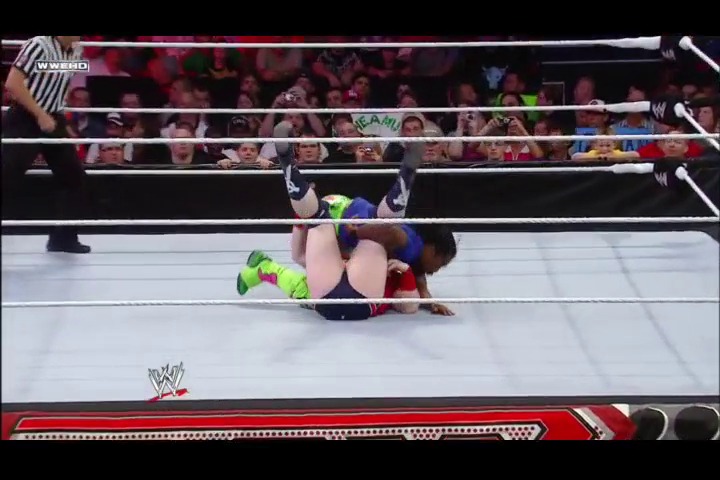 A frame from WWE Raw (April 25, 2011) at 39:34. A wrestler in neon green and pink attire lies on the white WWE ring canvas during a match, with the crowd visible in the background behind the ropes and WWE branding displayed at the bottom of the screen.