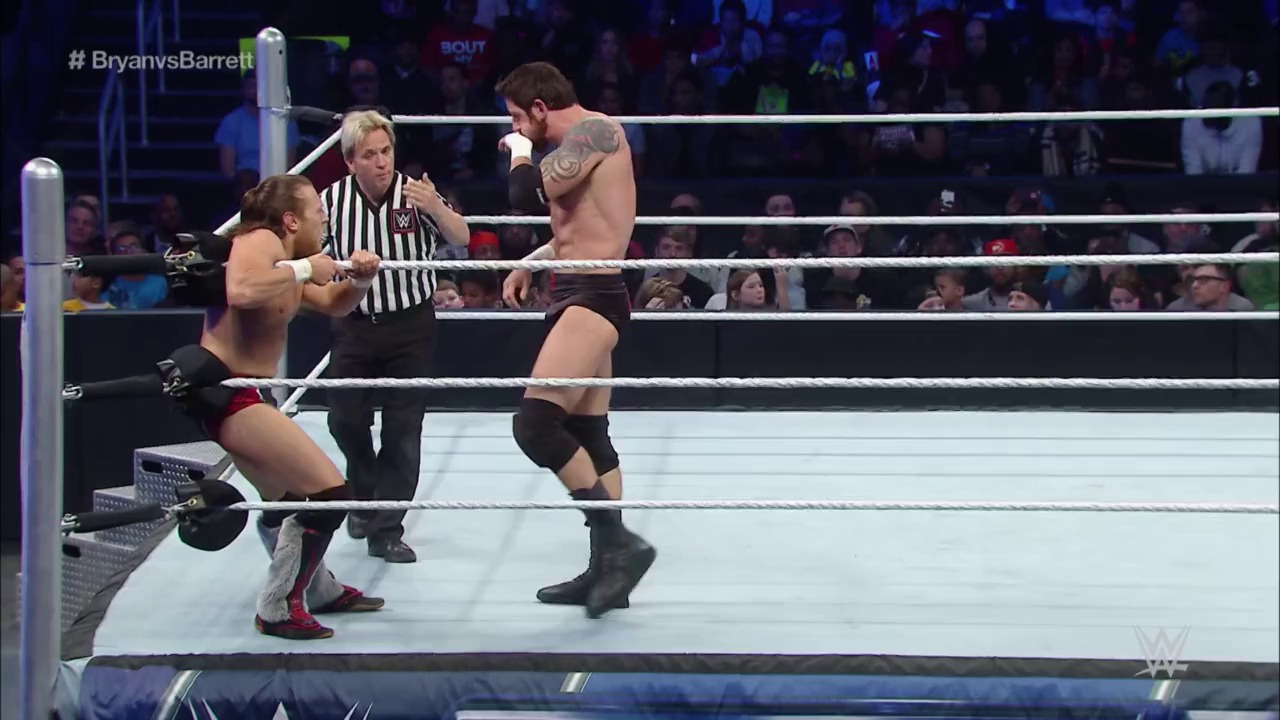 A frame from WWE SmackDown (February 26, 2015) at 36:14. A WWE wrestling match is underway in the ring with two shirtless male wrestlers and a referee in a striped shirt. The crowd fills the arena in the background, and the hashtag "#BryanvsBarrett" is visible in the top left corner of the broadcast.