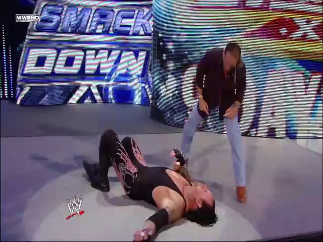 A frame from WWE SmackDown (March 19, 2010) at 1:22:49. # WWE SmackDown - March 19, 2010

A wrestler lies on the mat while another stands nearby during a WWE SmackDown match. The "SmackDown" logo and WWE branding are visible on the illuminated screen in the background.