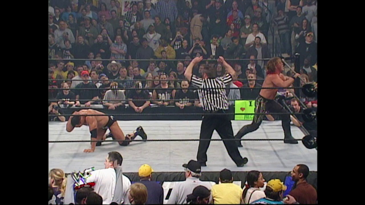 A frame from WWE Raw (April 4, 2002) at 1:23:02. A WWE referee in striped shirt stands in the center of the ring with arms raised, signaling a decision. Multiple wrestlers are visible in and around the ring, with an enthusiastic crowd in the background filling the arena stands.
