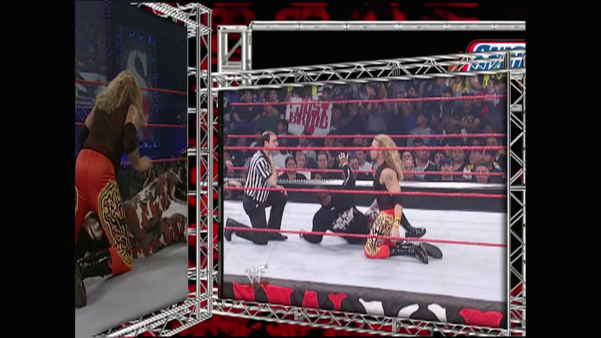 A frame from WWE Raw (March 12, 2001) at 24:43. A WWE wrestler lies on the canvas during a match while a referee stands nearby. The scene is captured on a television screen, with another wrestler visible outside the ring on the left side of the frame.