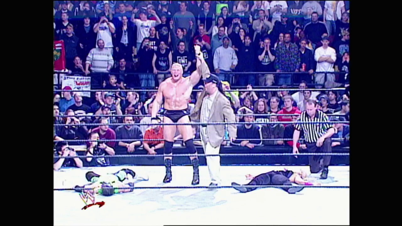 A frame from WWE Raw (March 21, 2002) at 1:00:26. A shirtless wrestler stands victorious in the ring with his fist raised, while an opponent lies defeated on the mat. A referee in striped shirt stands nearby as the crowd cheers from the packed arena seating.