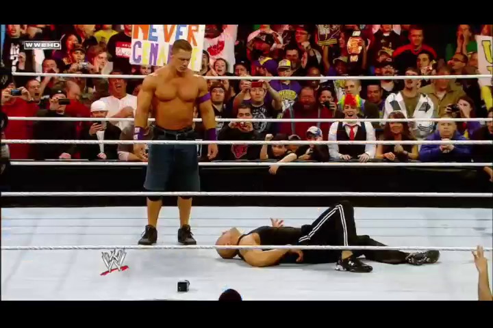 A frame from WWE Raw (March 28, 2011) at 1:40:05. A shirtless WWE wrestler stands in the ring looking down at his opponent lying on the mat, while a crowd of spectators watches from behind the ropes. The WWE logo is visible on the ring canvas.