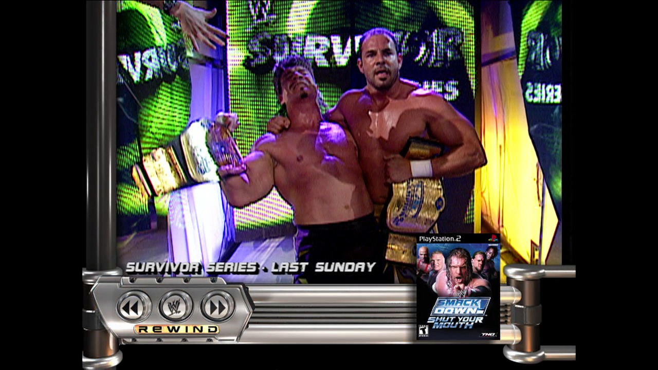 A frame from WWE Raw (November 21, 2002) at 22:28. Two shirtless wrestlers display championship belts in a brightly lit WWE ring, with vibrant green and purple LED screens behind them. The interface shows this is from a PlayStation 2 game featuring WWE SmackDown, with playback controls visible at the bottom.