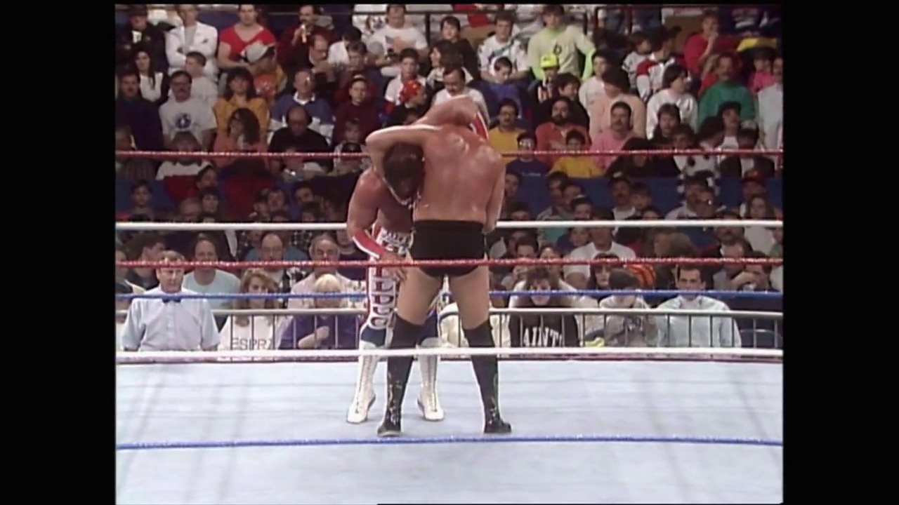 A frame from Royal Rumble (1992) at 1:30:55. A shirtless wrestler in red and black attire stands in a WWF wrestling ring, with a large crowd visible in the background behind the ropes. The classic wrestling ring setup features the distinctive red ropes and blue mat typical of early 1990s WWE events.