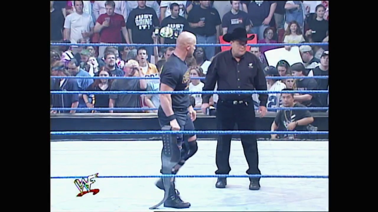 A frame from WWE SmackDown (April 5, 2001) at 1:01:57. A WWE wrestler in black attire stands in the blue-roped ring facing a referee in a black shirt and cowboy hat, with an enthusiastic crowd visible in the background. The WWE logo appears in the lower left corner of the broadcast.