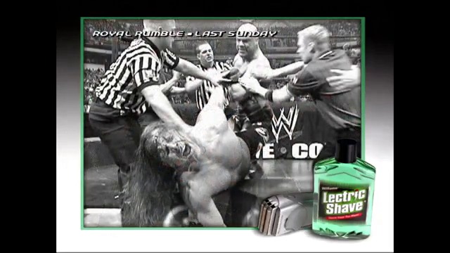 A frame from WWE SmackDown (February 4, 2005) at 12:44. A wrestler lies on his back in the ring during a Royal Rumble match while referees and other wrestlers gather around him. WWE and Llectric Shave branding appear in the corners of the black-and-white frame.