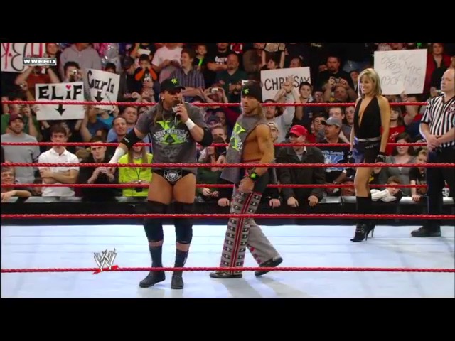 A frame from WWE Raw (January 28, 2008) at 39:18. A WWE wrestler in green and black attire performs in the red-roped ring while a referee and crowd watch from the stands. Spectators hold signs including one reading "CHRISSSSS" as the match unfolds on the illuminated canvas.