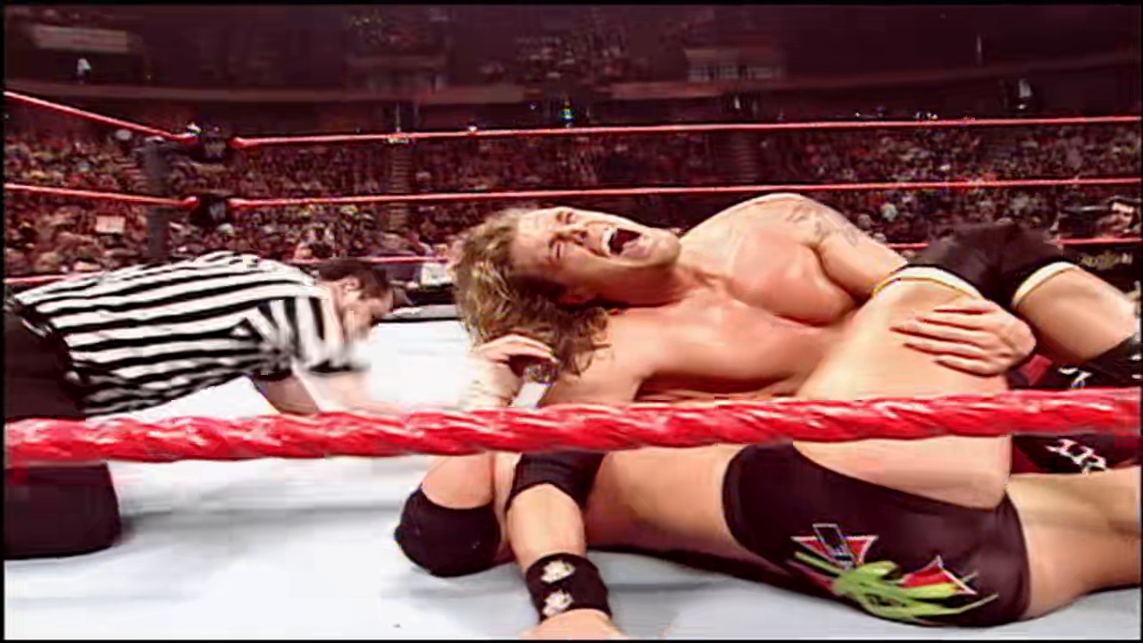A frame from WWE Raw (January 8, 2007) at 0:58. # WWE Raw Wrestling Match

A professional wrestling match is underway in a packed arena, with two wrestlers grappling on the red and white mat inside the ring. A referee in a striped shirt observes the action as the crowd fills the background stands.