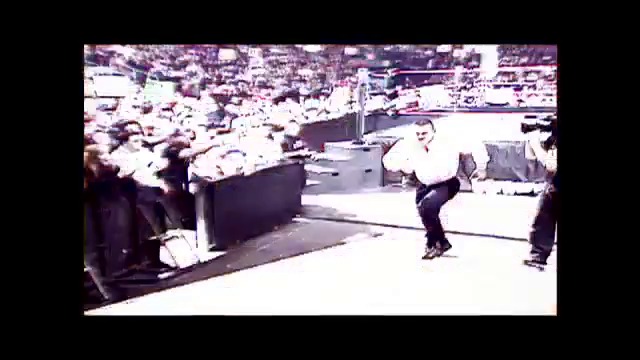A frame from WWE SmackDown (January 20, 2005) at 1:14:21. A wrestler in white shirt and dark pants performs in a WWE ring surrounded by an enthusiastic crowd. The arena is filled with spectators in the background, with the wrestling ring prominently featured in the center of the frame.