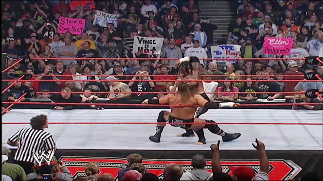A frame from WWE Raw (October 1, 2007) at 47:56. A shirtless wrestler performs in a WWE Raw ring surrounded by red ropes, while a referee in striped shirt officiates nearby. The crowd in the background holds various signs, including one that reads "Vince is Hot," with the WWE logo visible on the ring apron.