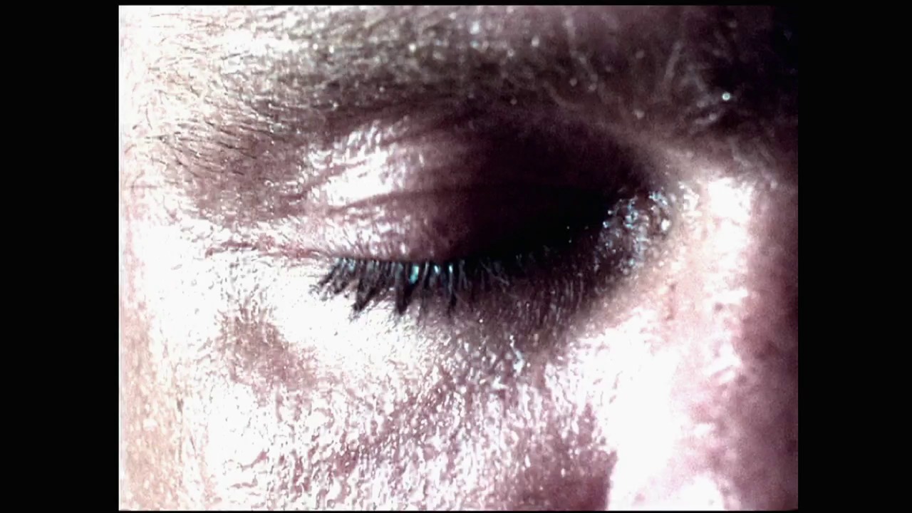 A frame from Survivor Series (2003) at 0:52. A close-up shot of a wrestler's face covered in sweat and grime, with visible facial hair and an intense expression during an in-ring moment at Survivor Series 2003.