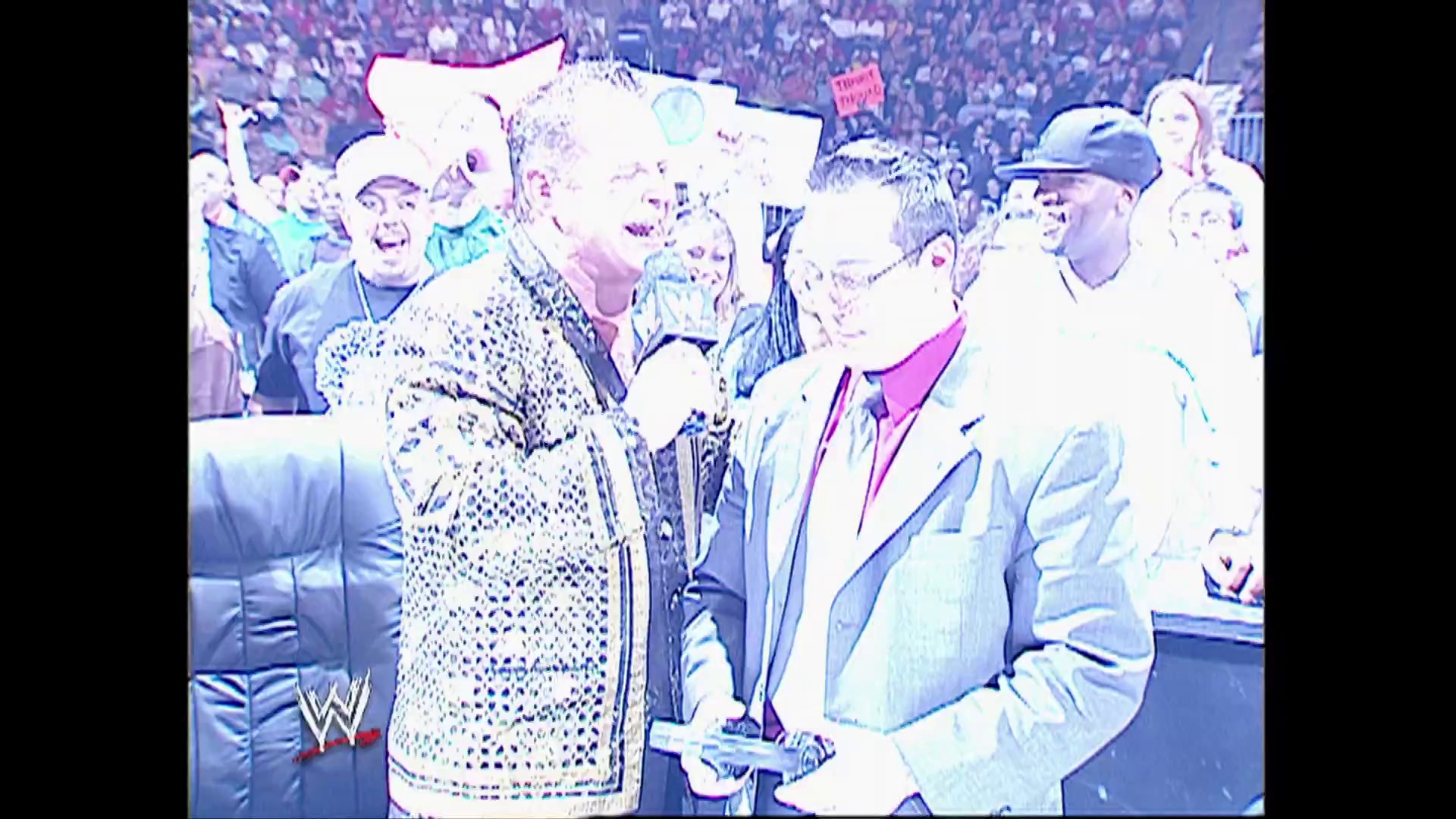 A frame from WWE Raw (May 1, 2006) at 1:10:53. A WWE wrestler in an ornate sequined jacket stands in the ring surrounded by a large crowd, while another person in a light blazer and hat stands nearby. The WWE Raw logo is visible in the lower left corner of the broadcast.