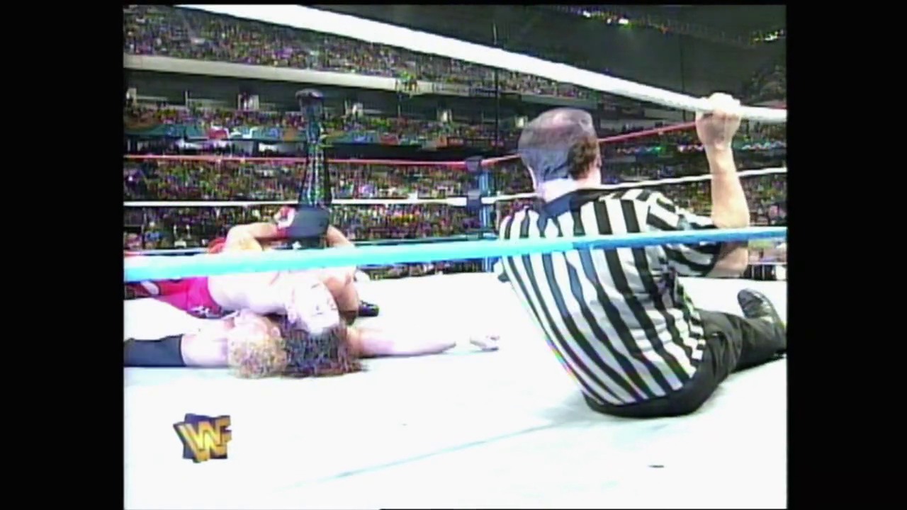 A frame from WWE Royal Rumble 1997 (1997) at 2:51:45. A referee in black and white stripes counts over a wrestler lying on the mat in a WWE ring, with a packed stadium crowd visible in the background and the WWF logo displayed in the corner.
