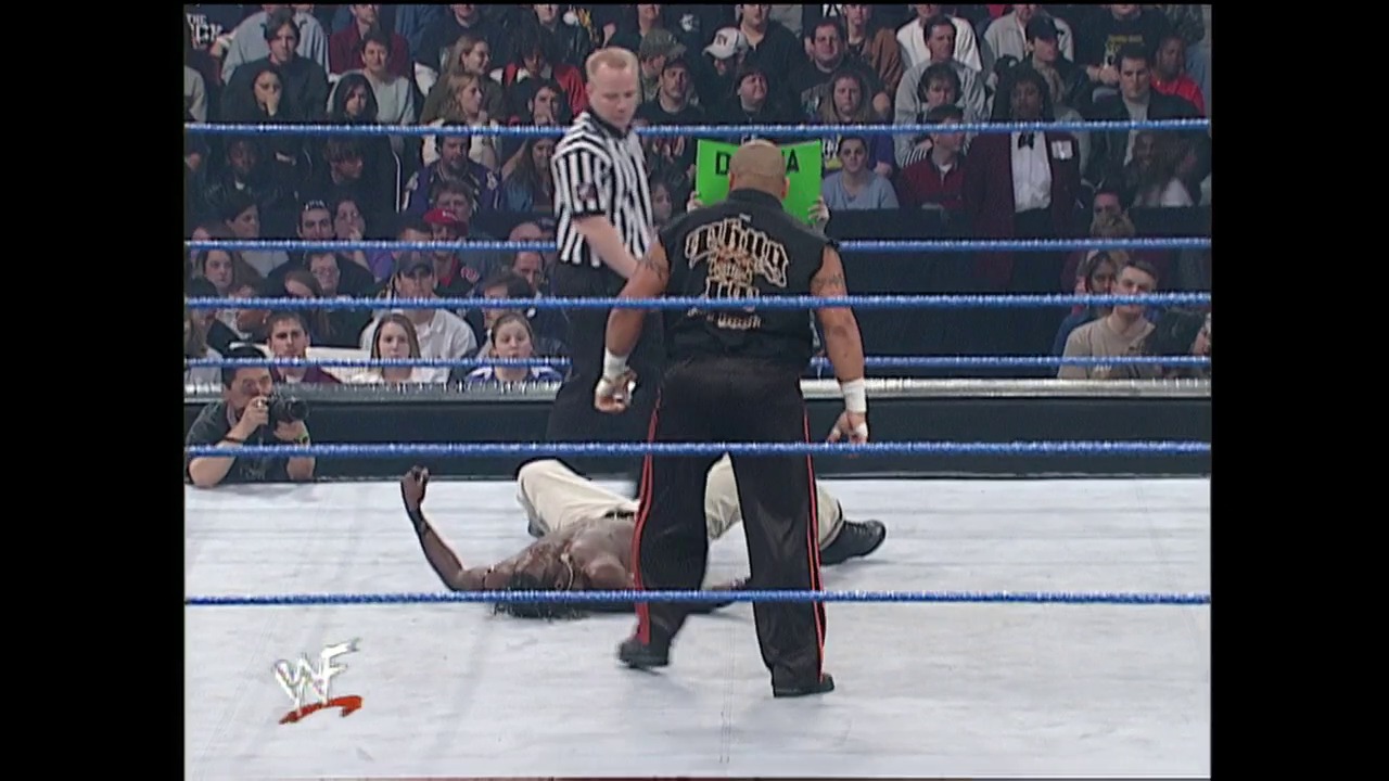 A frame from WWE SmackDown (January 25, 2001) at 50:25. # WWE SmackDown Ring Action

A wrestler lies on the mat while another stands over him in the WWE ring, with a referee in a striped shirt observing the match. The blue-roped ring is surrounded by a packed crowd, and the WWF logo appears in the lower left corner.