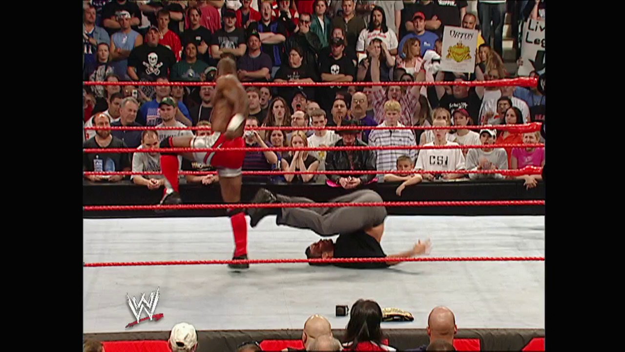 A frame from WWE Raw (April 26, 2004) at 1:06:26. A WWE wrestler lies on the mat inside the red-roped ring during an intense match, while another wrestler stands nearby. The crowd fills the arena seats in the background, with the WWE logo visible at ringside.