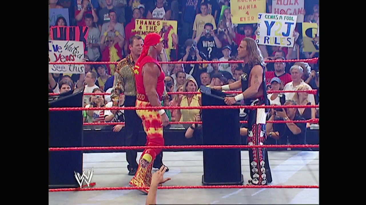 A frame from WWE Raw (August 8, 2005) at 1:21:20. Two wrestlers face off in a WWE Raw ring surrounded by enthusiastic fans holding signs. One wrestler wears a red and yellow outfit while the other sports black attire, with the crowd visible behind the red ropes.