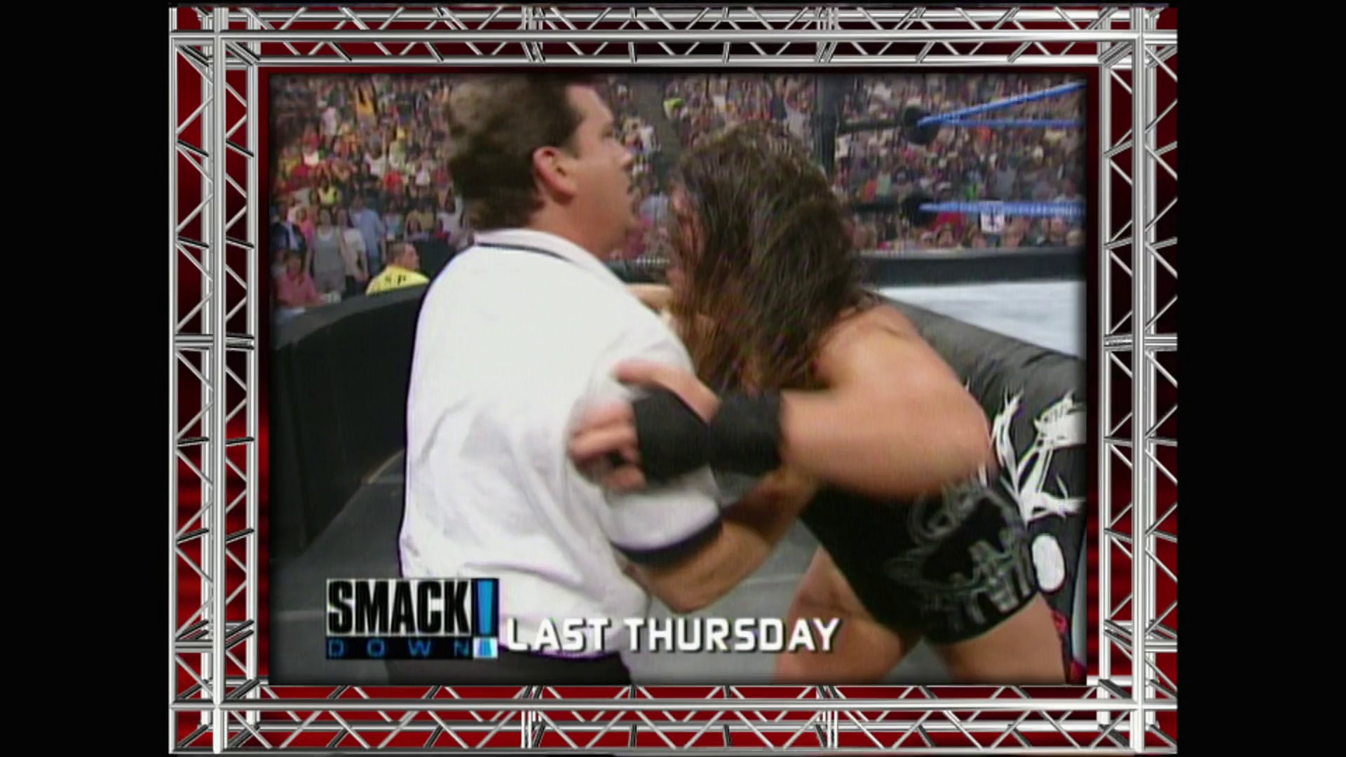 A frame from WWE Raw (July 16, 2001) at 1:23:55. A WWE wrestler in black attire with arm bands grapples with an opponent in a white shirt during a match, with a packed crowd visible in the background. The "SmackDown" logo and "Last Thursday" text appear at the bottom of the screen.