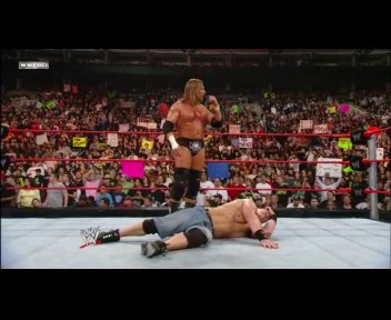 A frame from WWE Raw (February 25, 2008) at 1:32:26. A shirtless wrestler stands over a fallen opponent in the WWE ring, with a packed crowd visible in the background holding signs. The arena is filled with spectators under bright lighting during an intense match moment.