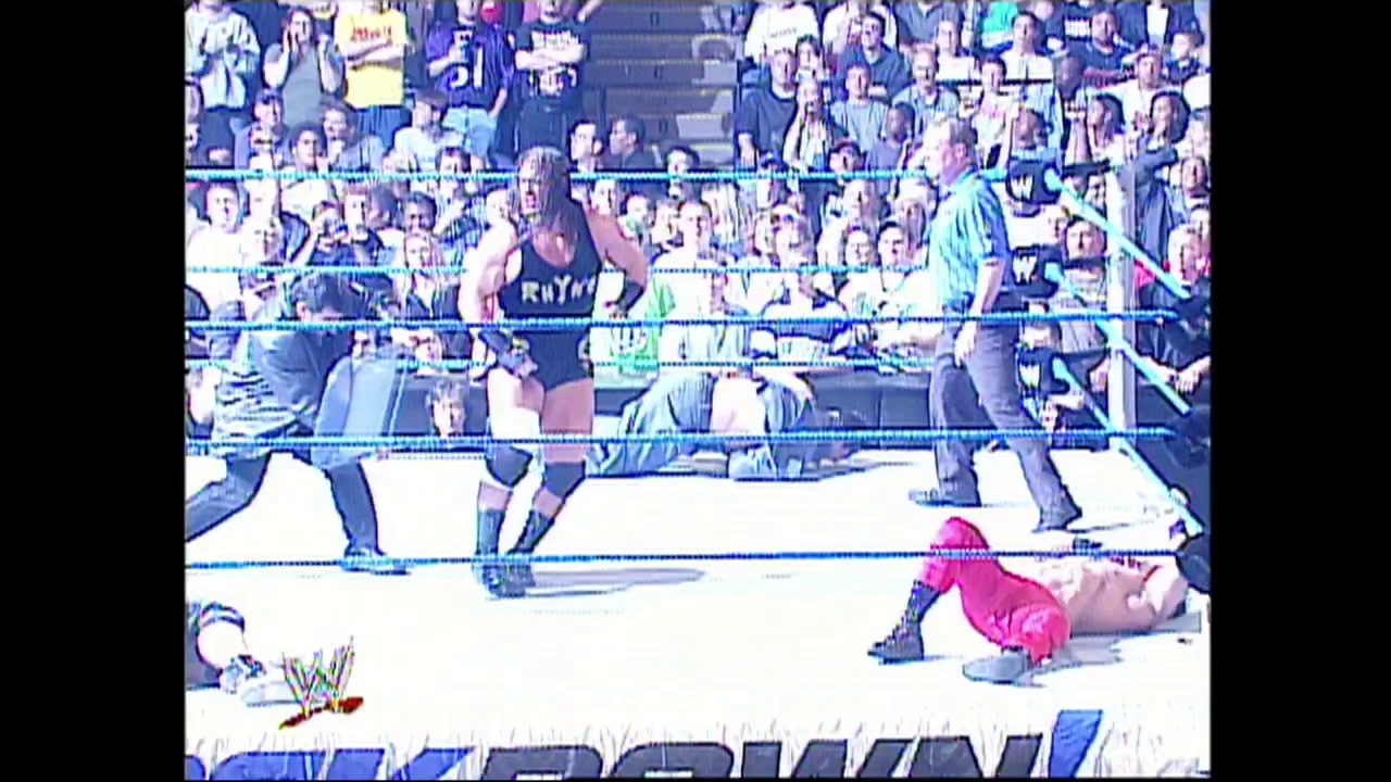 A frame from WWE SmackDown (May 15, 2003) at 44:28. # WWE SmackDown Ring Action

A wrestler in pink attire is grounded in the ring while opponents stand nearby, with a full crowd visible in the bleachers behind the ropes. The WWE logo is visible in the lower left corner of the broadcast.