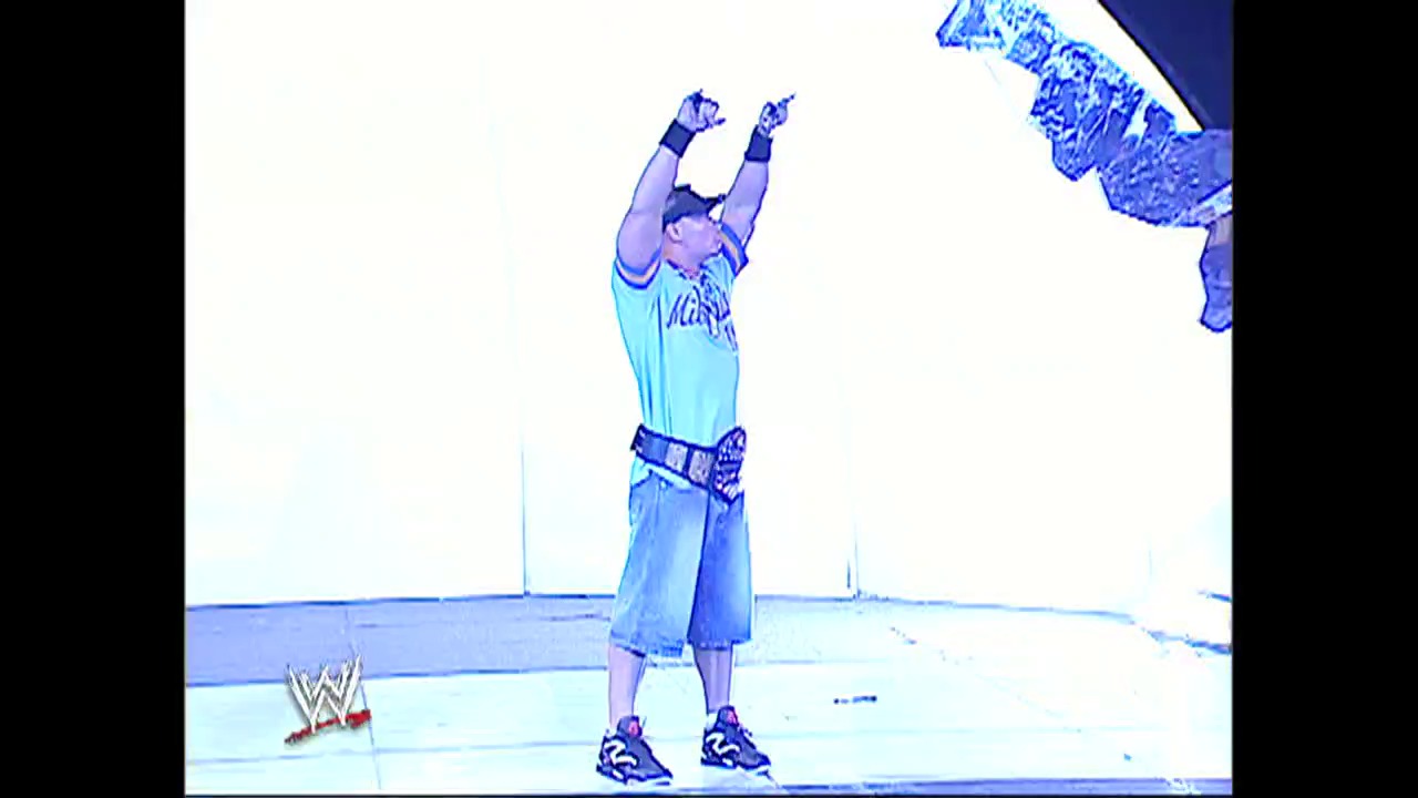A frame from WWE SmackDown (May 27, 2004) at 1:13:46. A WWE wrestler stands triumphantly in the ring with both arms raised in victory, wearing light blue attire and a decorative belt. The WWE logo is visible in the lower left corner of the broadcast.
