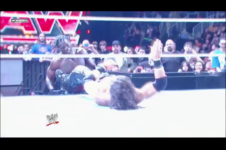 A frame from WWE Raw (April 11, 2011) at 1:19:59. A WWE wrestler lies on their back in the ring during an intense match, with their opponent standing over them. The crowd watches from the stands while the WWE logo and broadcast graphics are visible at the bottom of the screen.
