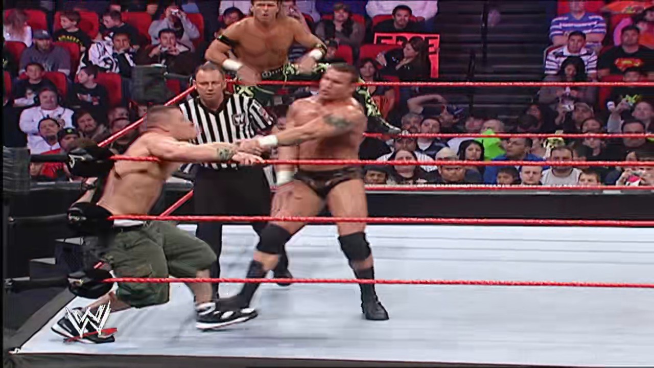 A frame from WWE Raw (February 26, 2007) at 1:19:59. A WWE wrestler in dark pants applies a submission hold on an opponent in the ring while a referee in striped shirt observes. The crowd fills the arena seats in the background as red ropes frame the action.