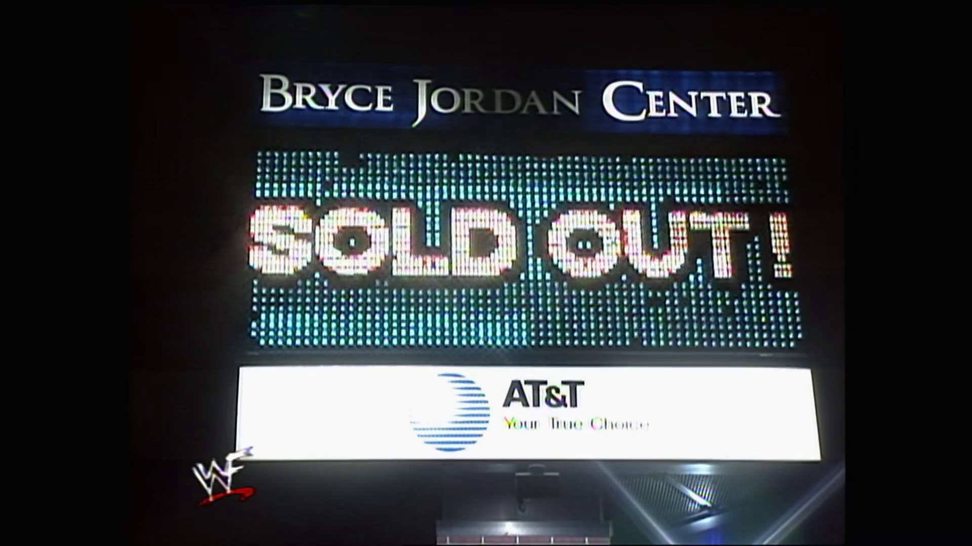 A frame from WWE Raw (November 8, 1999) at 27:01. # Visual Description

A large LED scoreboard displays "BRYCE JORDAN CENTER SOLDOUT" with the AT&T logo and "Your True Choice" slogan below. The WWE logo is visible in the lower left corner, indicating this is from a professional wrestling broadcast.