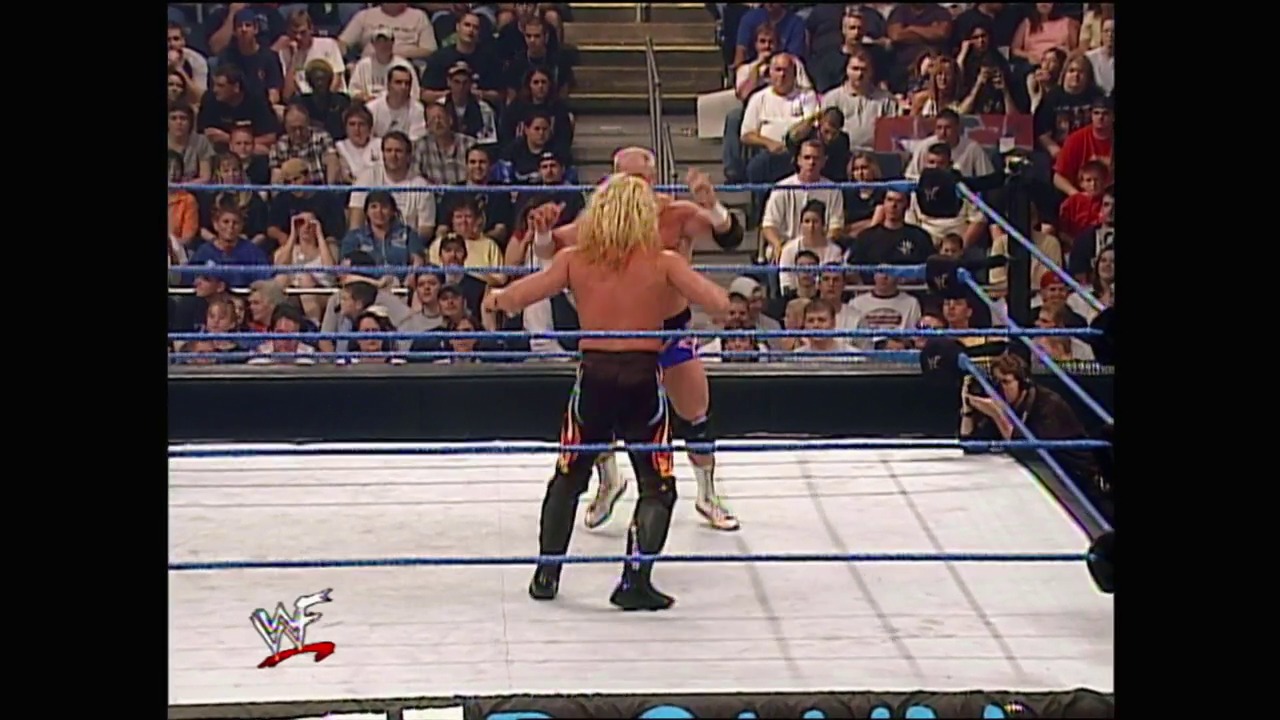 A frame from WWE SmackDown (May 25, 2000) at 37:23. # WWE SmackDown Wrestling Match

A shirtless blonde wrestler stands in the ring with arms outstretched, facing an opponent in dark pants. The packed arena crowd fills the stands behind the blue-roped wrestling ring, with the WWF logo visible on the mat.