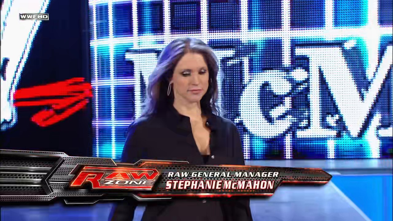 A frame from WWE Raw (January 19, 2009) at 1:25:08. A woman in a black blazer stands in the WWE Raw ring with purple-tinted hair and hoop earrings. The lower third displays a nameplate identifying her as "Stephanie McMahon, Raw General Manager," with the RAW Zone logo and blue LED screens visible in the background.