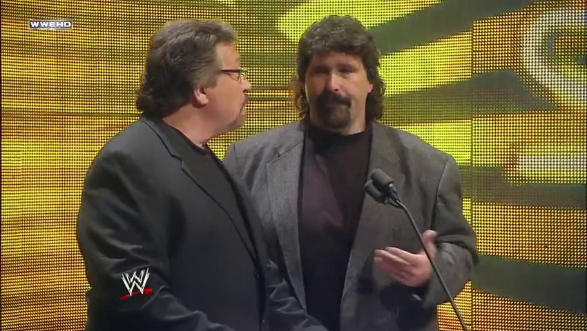 A frame from WWE Raw (December 12, 2011) at 18:05. Two men in business attire stand on stage against a yellow LED backdrop with microphones. The WWE logo is visible in the lower left corner, indicating this is from a professional wrestling broadcast.
