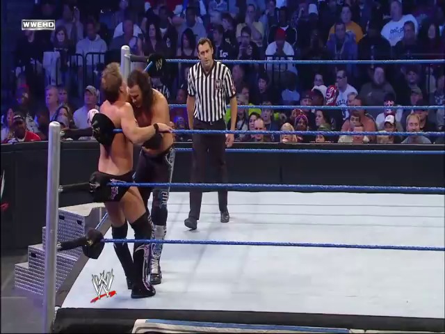 A frame from WWE SmackDown (February 5, 2010) at 48:44. Two wrestlers grapple in the ring during a WWE SmackDown match, with a referee in striped shirt observing nearby. The crowd fills the arena in the background while the WWE logo is visible on the ring apron.