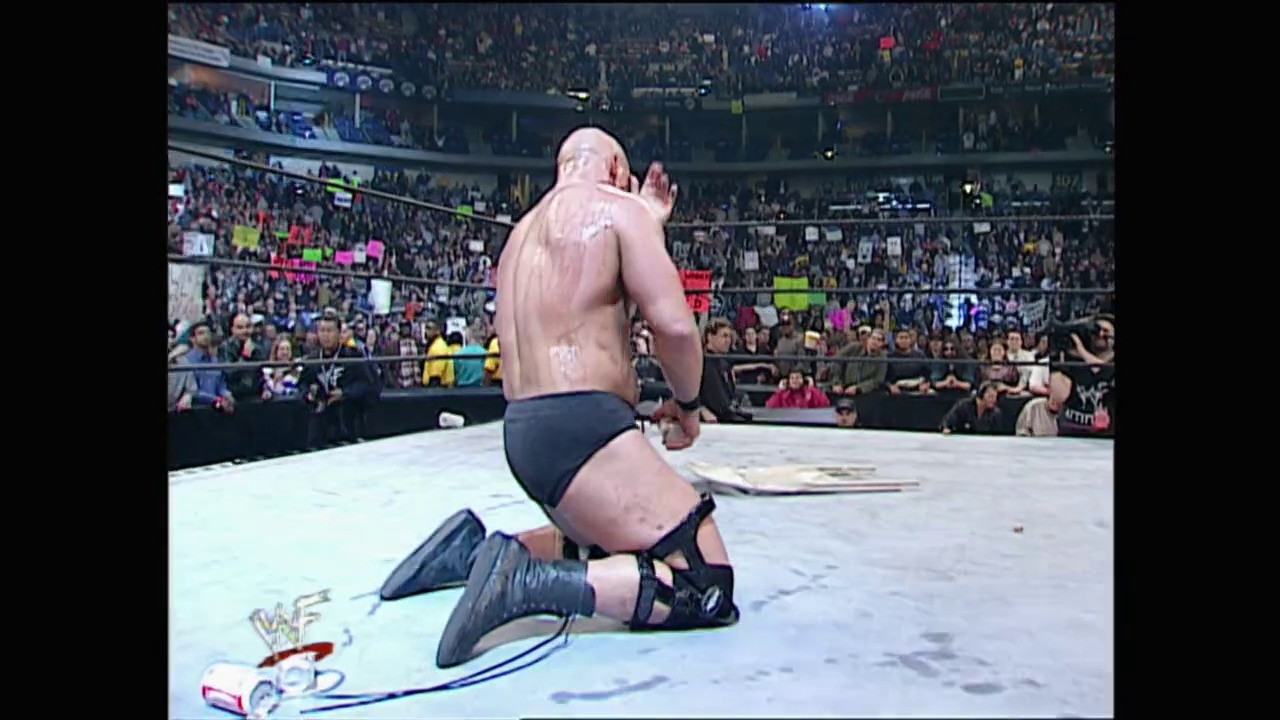 A frame from Royal Rumble (2001) at 2:49:38. A shirtless wrestler kneels in the wrestling ring during the Royal Rumble 2001 event, with a packed arena visible in the background and the WWF logo displayed on the mat.