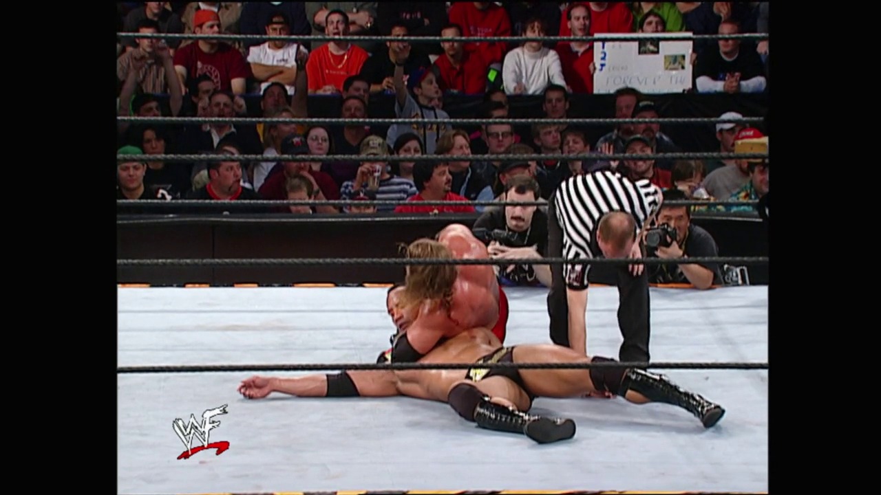 A frame from Royal Rumble (2002) at 1:10:29. # Royal Rumble 2002 - Wrestling Action

A wrestler lies on the mat in the WWE ring while a referee stands nearby. The crowd fills the arena stands in the background, with the WWF logo visible in the lower left corner of the broadcast.