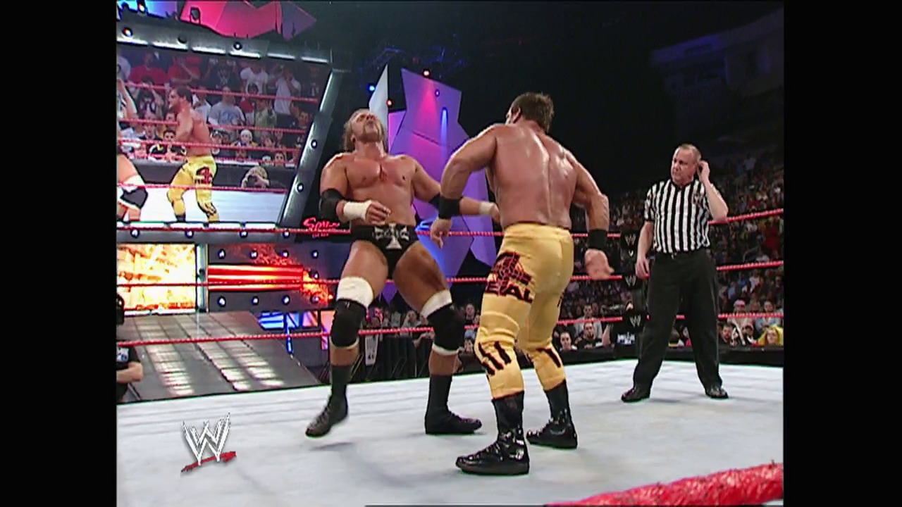 A frame from WWE Raw (March 14, 2005) at 1:09:04. Two shirtless wrestlers face off in a WWE ring during an intense match, with one wearing yellow pants and the other in black. A referee in a striped shirt stands nearby as the crowd watches from the arena seats, with colorful stage lighting and WWE graphics visible in the background.