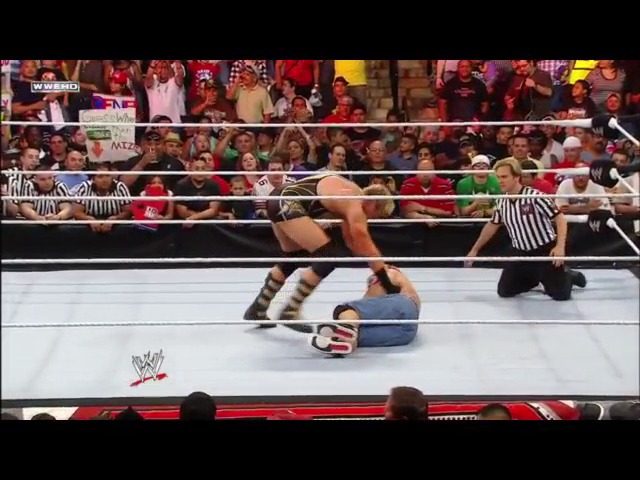 A frame from WWE Raw (May 16, 2011) at 1:15:40. A WWE wrestler executes a move on an opponent in the ring during Raw, with referees monitoring the action and an enthusiastic crowd visible in the background behind the ropes.