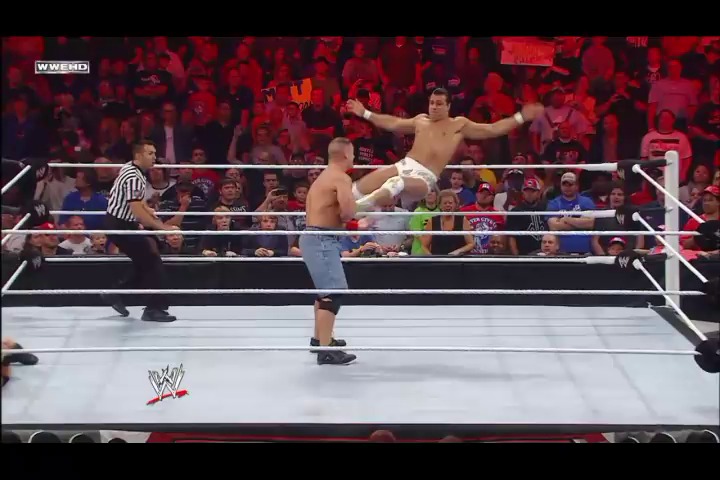A frame from WWE Raw (September 26, 2011) at 51:57. A WWE wrestler stands with arms raised in the ring while his opponent lies on the mat during Raw. The referee watches from the side as the red-lit crowd cheers in the background.