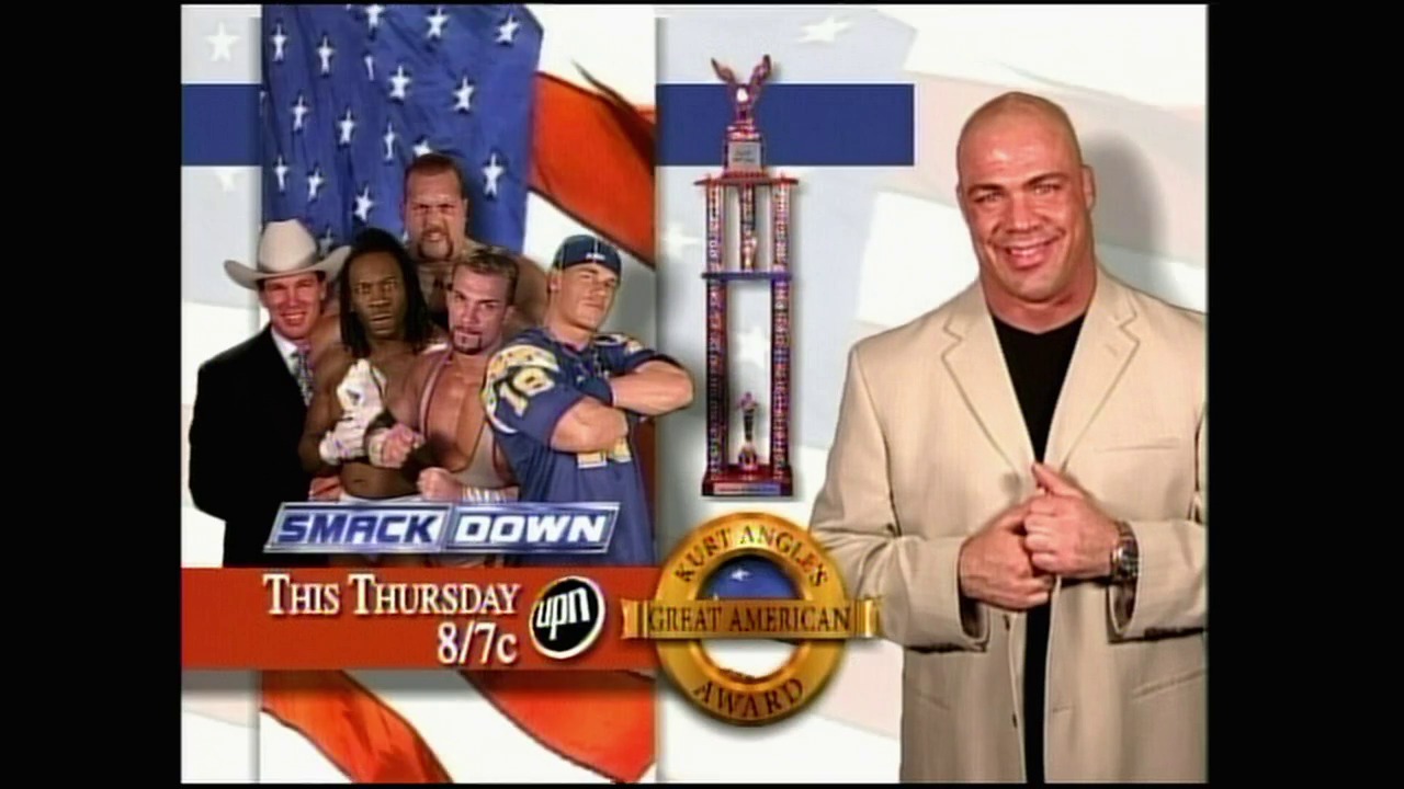 A frame from WWE Raw (April 5, 2004) at 1:06:19. A promotional graphic for WWE SmackDown features four wrestlers posed against an American flag backdrop on the left, while a man in a beige blazer stands on the right next to the "Great American" award trophy. Text indicates the event airs "This Thursday 8/7c" on UPN.